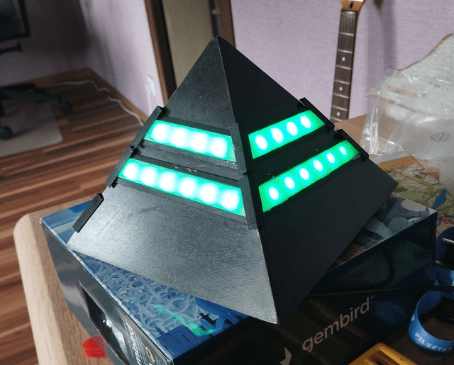 Black pyramid with lit green leds around the sides